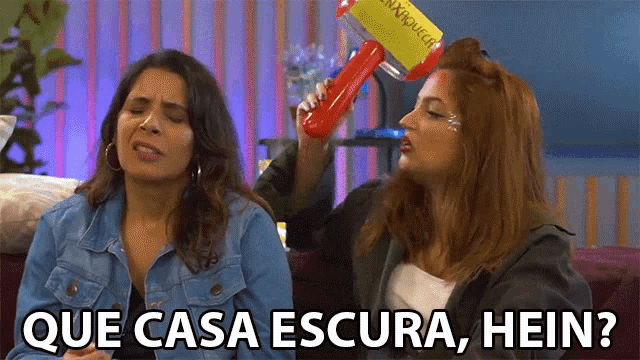 two women are sitting on a couch and one says que casa escura