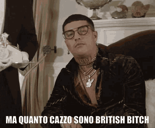 a man wearing glasses is sitting in a chair with the words ma quanto cazzo sono british bitch above him
