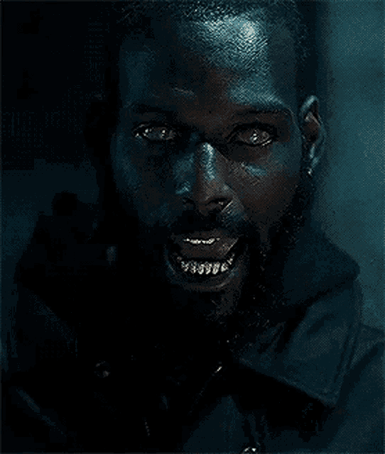 a man with a beard and gold teeth is smiling at the camera .