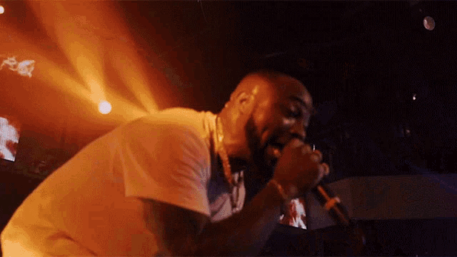 a man in a white shirt is singing into a microphone on a stage