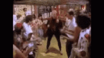 a group of people are dancing in a room with a sign in the background .