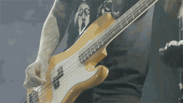 a man playing a bass guitar with a shirt that says scream