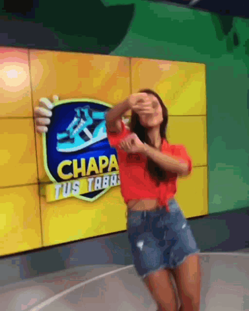 a woman dancing in front of a sign that says chapa tus taba