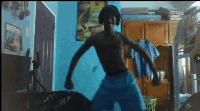 a man without a shirt is dancing in a room with blue walls