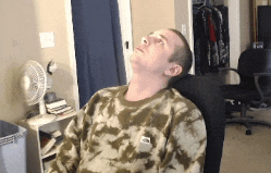 a man in a tie dye shirt is laying in a chair with his head up