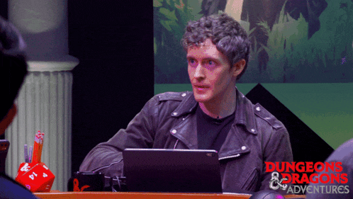 a man sitting at a table with a laptop and the words dungeons & dragons on the bottom