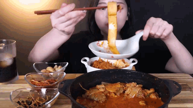 a woman is eating food with chopsticks and a bowl of food in front of her