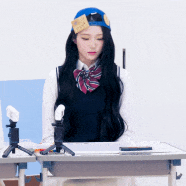 a girl sitting at a desk with a note on her hat that says " i love you "