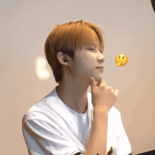a young man wearing ear buds and a white shirt has a yellow smiley face floating above his head