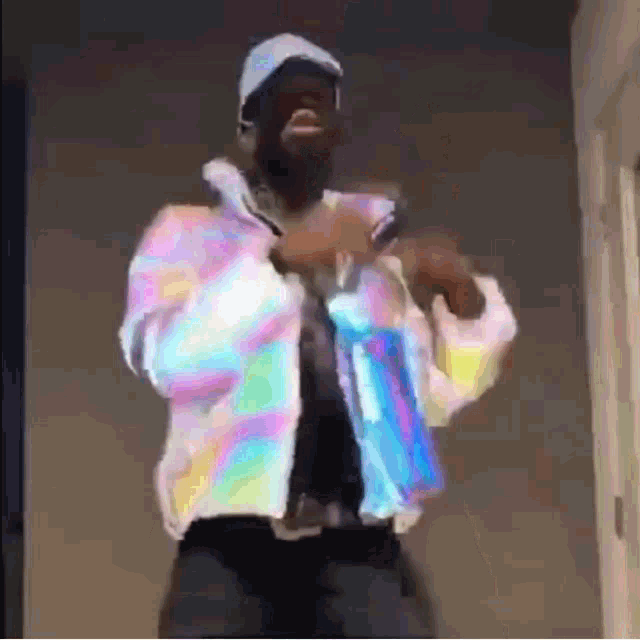 a man wearing a hat and a rainbow jacket is dancing .