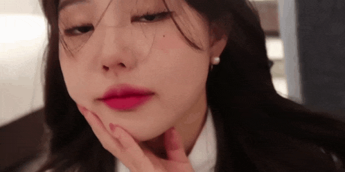 a close up of a woman 's face with a hand on her chin
