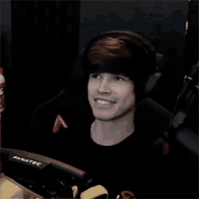 a young man wearing headphones is smiling while sitting in front of a fanatec computer monitor .