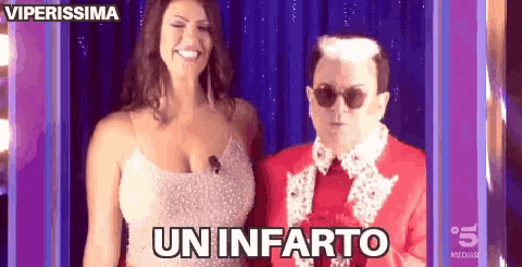 a man and a woman are standing next to each other and the man is wearing sunglasses and a red suit .