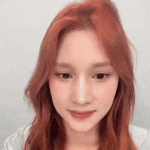 a close up of a woman with red hair and a white shirt .