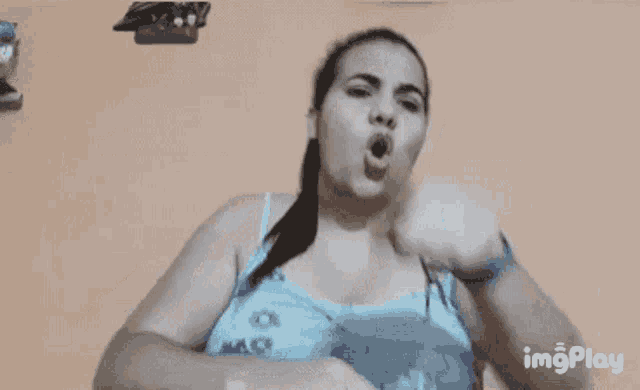 a woman in a blue tank top is flexing her muscles in a gif that says imgplay