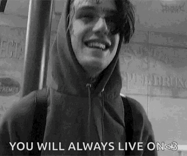 a black and white photo of a young man in a hoodie smiling and saying `` you will always live on < 3 '' .