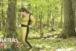 a man in a yellow suit is walking through the woods .