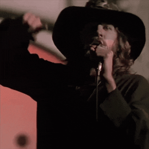 a man singing into a microphone with a cross on his neck