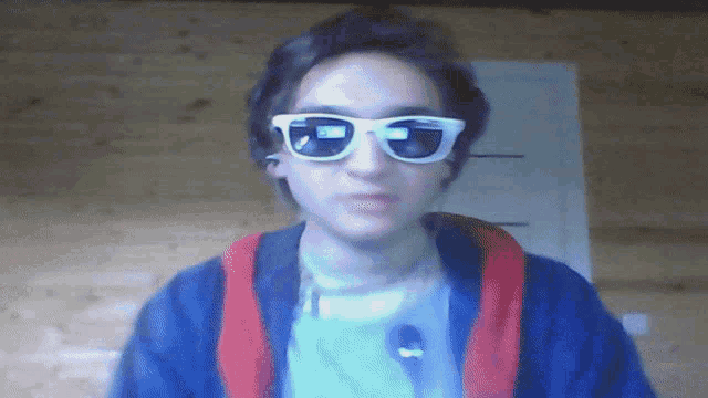 a young man wearing a blue jacket and white sunglasses with the letter e on the lens