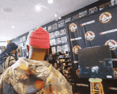 a man wearing a pink hat stands in front of a wall with looney tunes logos on it