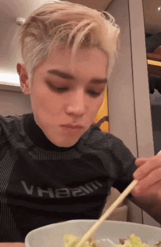 a man wearing a shirt that says vh82m is eating food