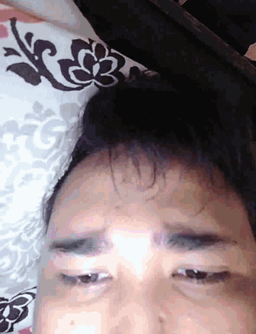 a close up of a man 's face with a pillow in the background
