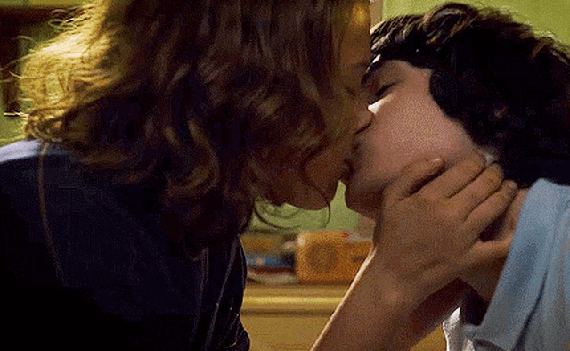 a woman and a man are kissing in a kitchen .