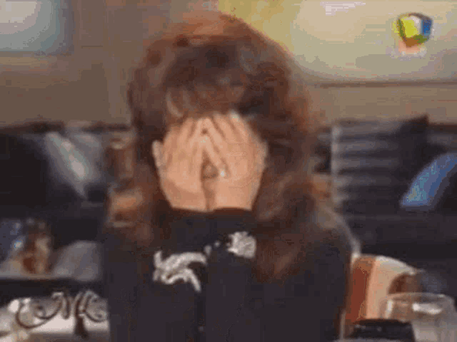 a woman is covering her face with her hands .