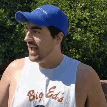 a man wearing a blue hat and a big ed 's tank top