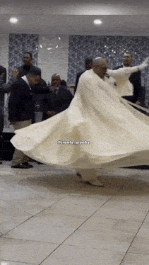 a man in a long white dress is dancing in front of a group of men with the caption @crente_aranha