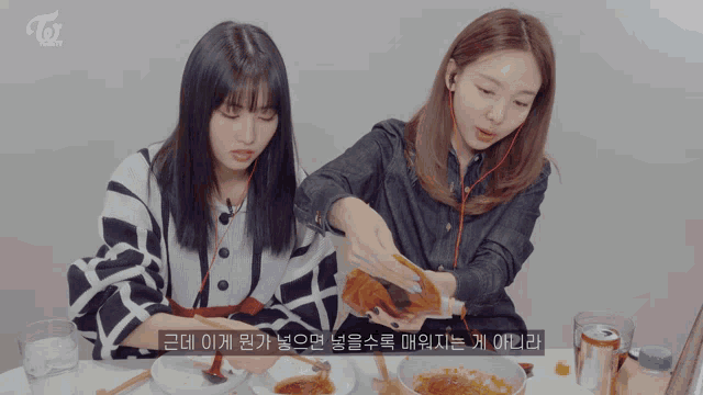 two girls are sitting at a table with a can of soda and a bowl of food with chopsticks