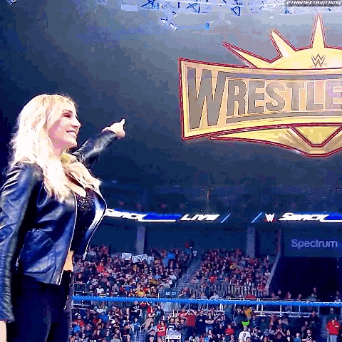 a woman is giving a thumbs up in front of a wrestle logo