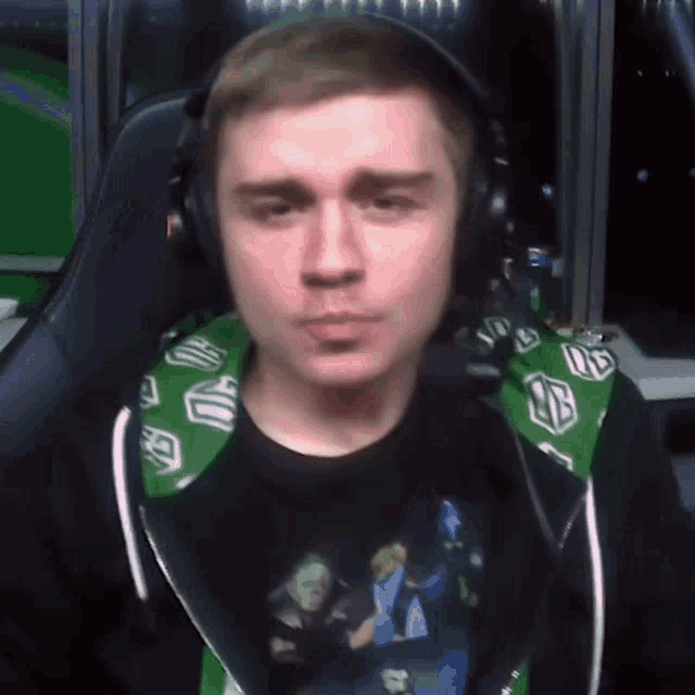 a man wearing headphones and a green hoodie is making a face .