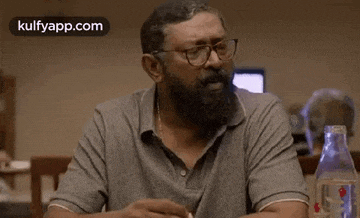a man with a beard and glasses is sitting at a table in a restaurant .