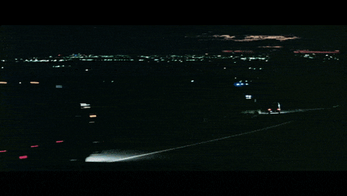 a car is driving down a highway at night with a city in the background