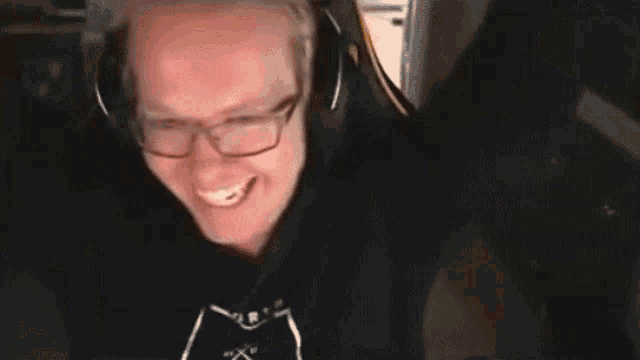 a man wearing headphones is smiling and making a peace sign .