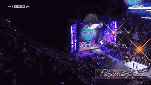 a wrestling match is being shown on a large screen and the words eddy speeding official are on the bottom right