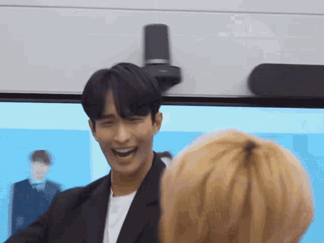 a man in a suit is laughing in front of a screen