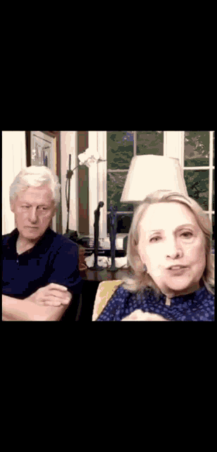 a man and a woman are sitting at a table in front of a lamp