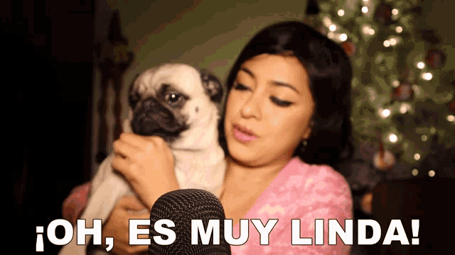 a woman holding a pug dog with the words oh es muy linda behind her