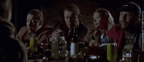 a group of people are sitting around a table with bottles and cans of beer .