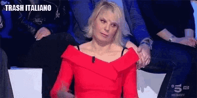 a woman in a red dress is sitting in a row of people .