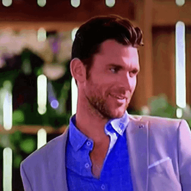 a man with a beard is wearing a blue shirt and a grey suit jacket .