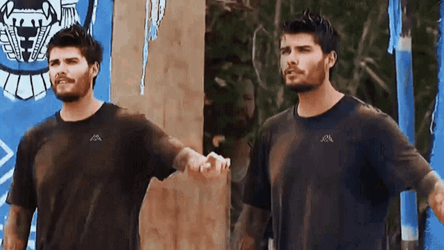 two men wearing kappa shirts shake hands in front of a blue flag