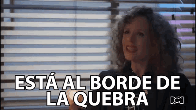 a woman sitting in front of a window with the words " esta al borde de la quebra " on the bottom