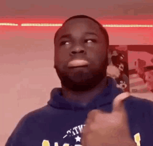 a man with a beard is giving a thumbs up while wearing a blue hoodie .