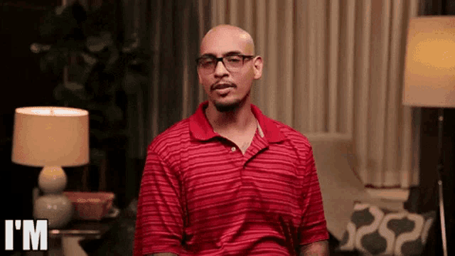 a man wearing glasses and a red shirt says " i 'm "