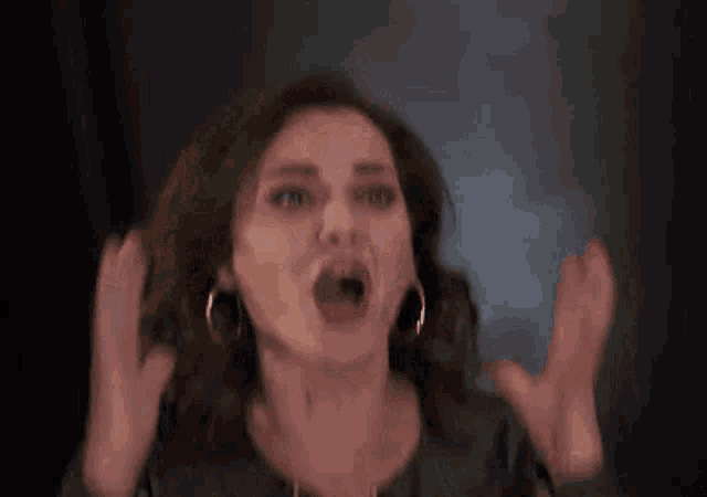 a close up of a woman making a funny face with her mouth open .