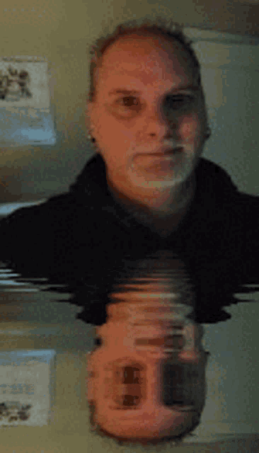 a man 's face is reflected in a mirror with a reflection of himself