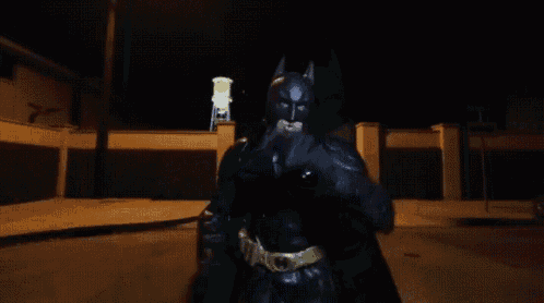 a man in a batman costume is standing on a street